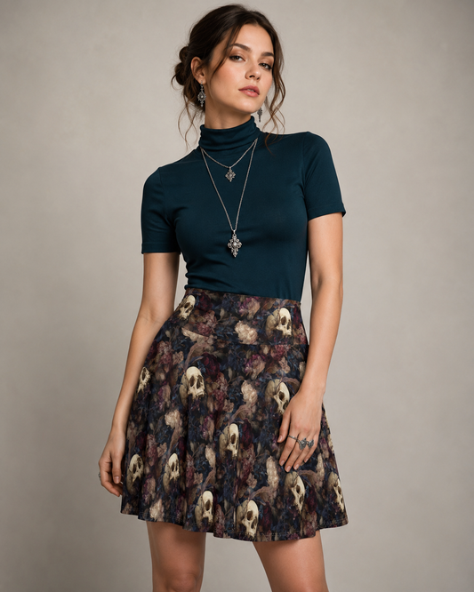 High-waisted skater skirt featuring a dark navy and burgundy floral pattern with antique ivory skulls and a subtly hidden written phrase. A woman modeling a dark teal short-sleeve mock neck top paired with a pleated high-waisted skater skirt featuring a dark floral and skull print, set against a plain gray studio background.