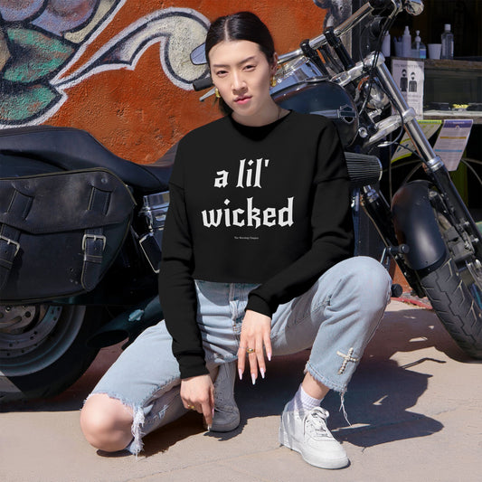 Person wearing a black sweatshirt with text, sitting in front of a motorcycle and colorful wall.